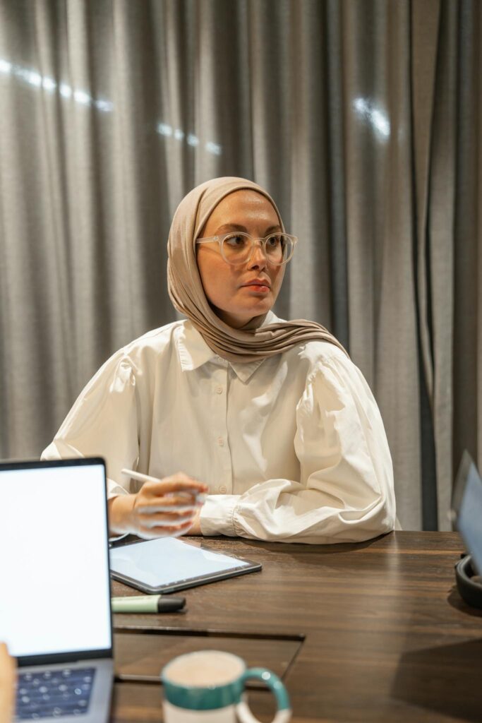 Middle Eastern woman in hijab working at a desk with a laptop, embodying professionalism.