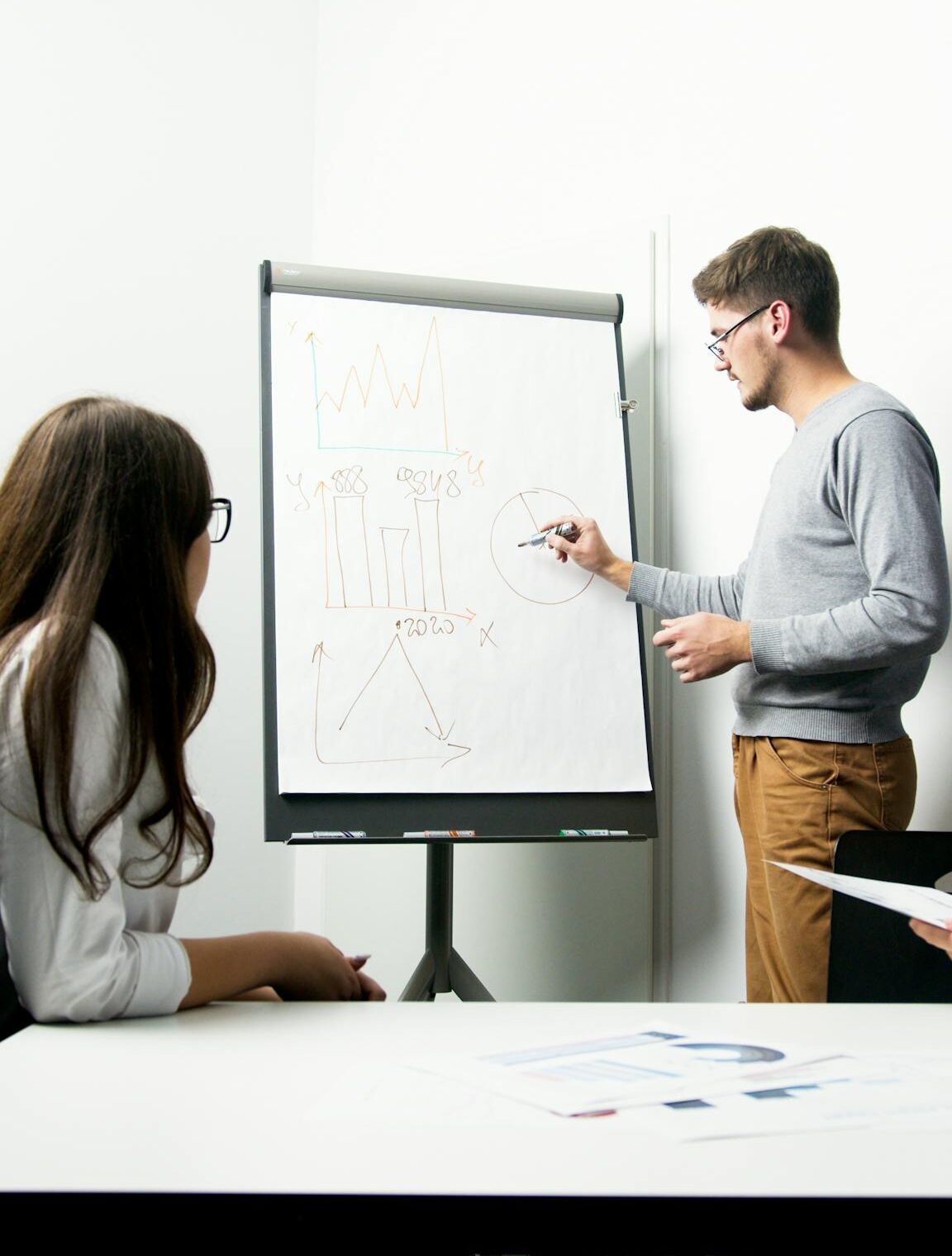 A businessperson giving a presentation with charts in a modern office environment.