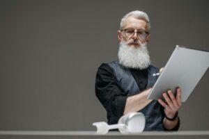 Bearded senior man in black long sleeves using a tablet, illustrating innovation and technology.